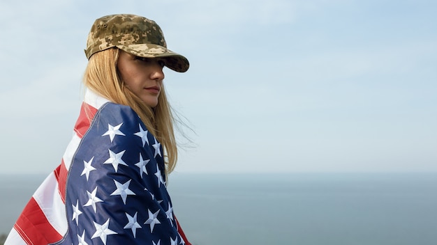 Femme civile dans la casquette militaire de son mari. Une veuve avec un drapeau des États-Unis est partie sans son mari. Jour du Souvenir aux soldats tombés au combat pendant la guerre. Le 27 mai est un jour commémoratif.