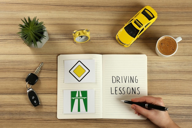 Femme avec classeur pour les leçons de conduite et les panneaux de signalisation à la vue de dessus de table en bois Réussite de l'examen de licence