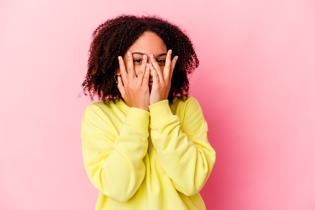 femme clignote à la caméra à travers les doigts