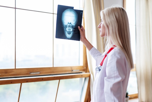 Femme clinicienne regardant la radiographie du crâne des patients