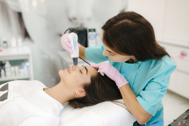 Femme à la clinique de spa de beauté cosmétique a la cosmétologie du matériel du visage. Femme faisant des procédures de beauté