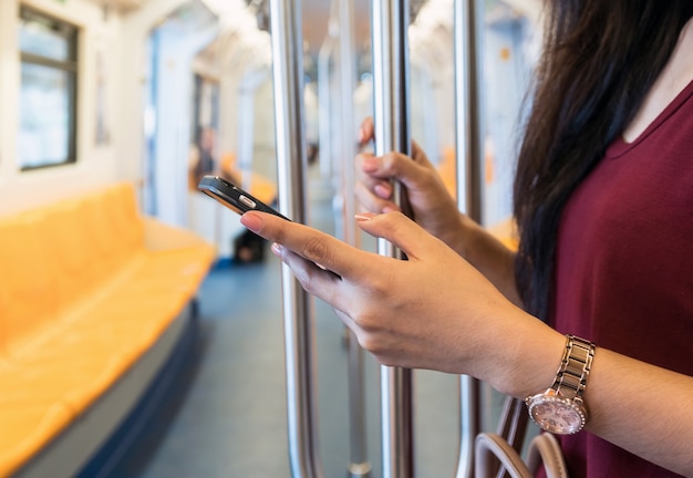 Femme CloseUp utilisant le téléphone mobile intelligent dans le BTS Skytrain