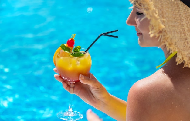 Femme avec cocktail près de la piscine. Mise au point sélective.