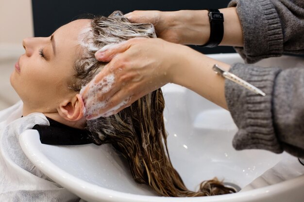 Photo femme avec coiffeur laver la tête au salon de coiffure