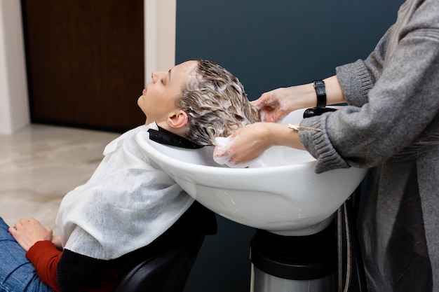 Photo femme avec coiffeur laver la tête au salon de coiffure