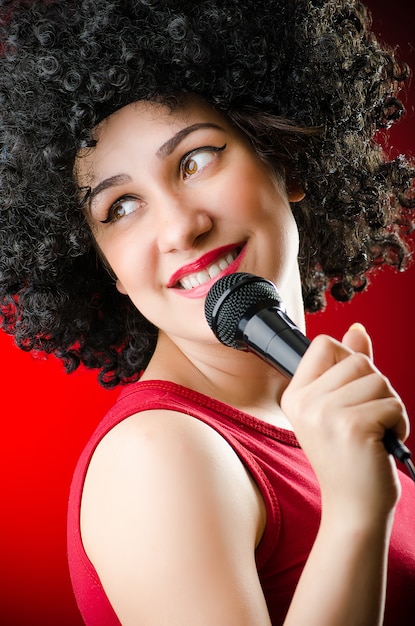 Femme avec une coiffure afro chantant au karaoké