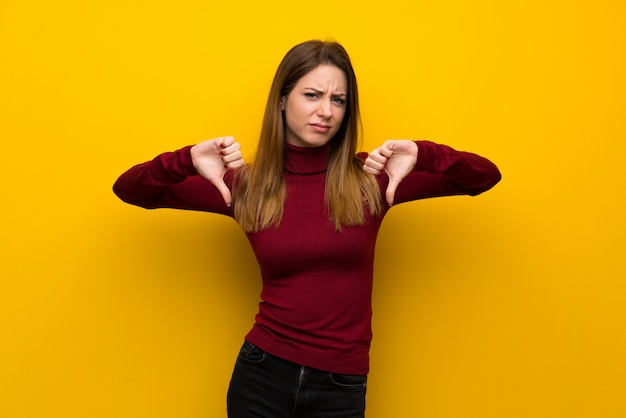 Femme, à, col roulé, sur, jaune, mur, projection, pouce bas