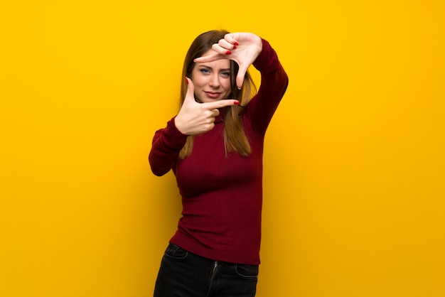 Femme avec col roulé sur le visage de mur jaune. Symbole d&#39;encadrement