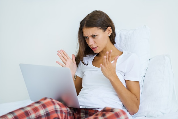 Femme en colère et ennuyeuse, ligne Internet cassée. Jeune femme étudiante regarder la vidéo en ligne webinaire apprendre sur ordinateur portable, emplacement dans la chambre de cours d'apprentissage en ligne à distance lit à la maison. Éviter les contacts sociaux.