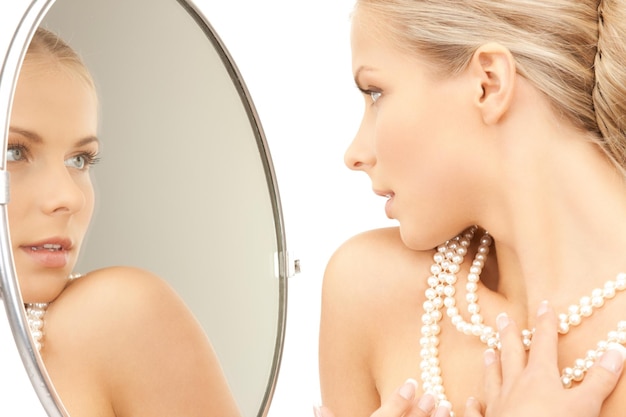 femme avec collier de perles regardant dans le miroir