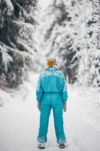 Femme en combinaison de ski dans la forêt enneigée pendant les vacances d'hiver à l'extérieur