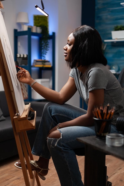 Photo femme avec des compétences en dessin à la main commençant à dessiner avec des crayons de couleur sur le lieu de création artistique. dessinateur afro-américain mettant la touche finale à des œuvres d'art faites à la main en studio.