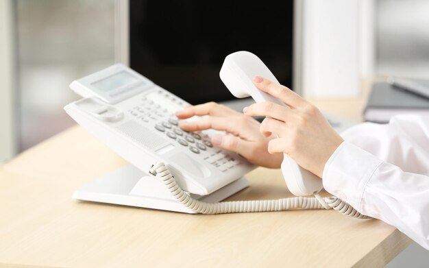 Femme composant le numéro de téléphone au bureau