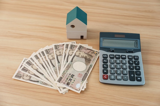 Femme comptant le billet de banque en yen japonais avec le modèle de maison Immobilier Accueil Hypothèque Japon trésorerie Récession fiscale Économie Inflation Financement des investissements et concepts d'épargne