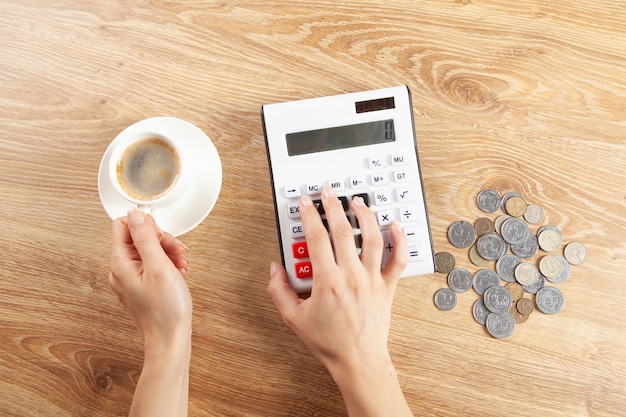 La femme compte sur une calculatrice et boit du café