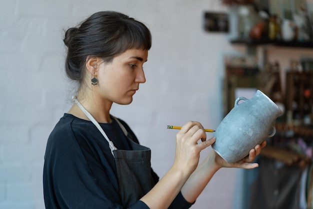 Une femme concentrée examine son produit manufacturé et propose un design individuel pour une boutique d'art