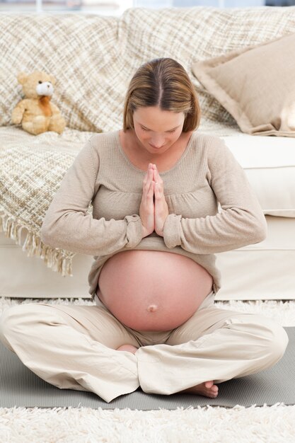 Femme concentrée, faire du yoga sur le sol de son salon