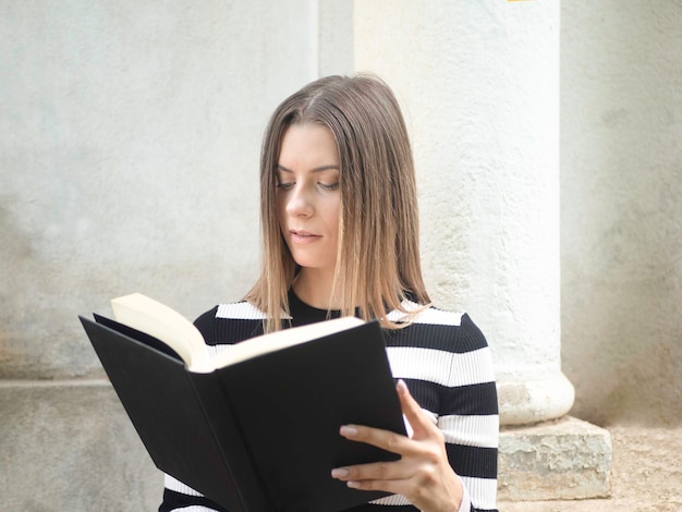 Femme concentrée lisant un livre dans la rue