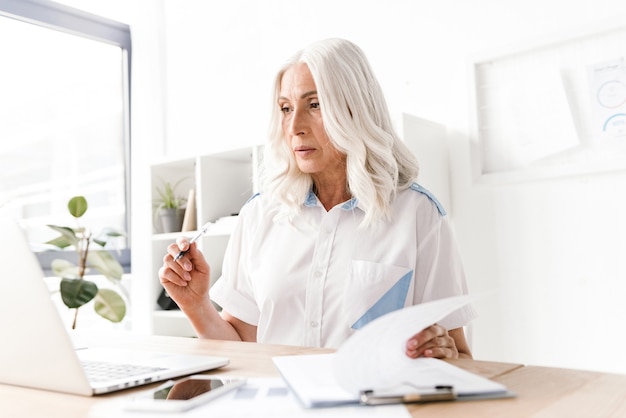 Femme concentrée mature, écrire des notes.