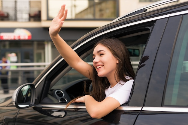 Femme de conducteur de voiture retourne comme signe d'adieu dans la rue