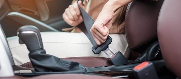 Femme conductrice main attachant la ceinture de sécurité pendant qu'elle était assise à l'intérieur d'une voiture et conduisait dans le voyage de sécurité routière et le concept de transport