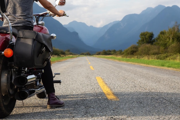 Femme conduisant une moto sur une route panoramique entourée de montagnes canadiennes