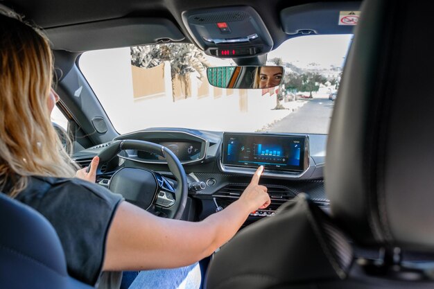 Femme conduisant la voiture électrique vérifiant l'énergie