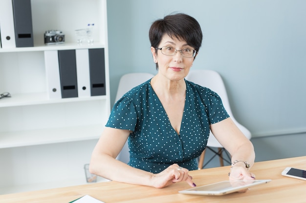 Femme confiante d'âge moyen travaille avec tablette au bureau