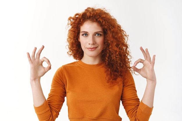 Photo une femme confiante s'assure que tout va bien une femme rousse ambitieuse motivée est déterminée à gagner montrer ok geste d'approbation sourire heureux affirmer le projet sous contrôle en jugeant le bon produit