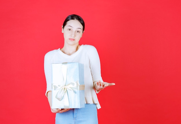 Femme confidentielle tenant une boîte-cadeau et a ouvert sa main