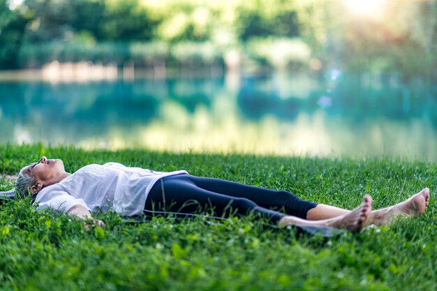 Femme consciente allongée au bord de l'eau en train de méditer