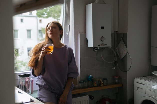 Une femme contemplative avec du thé près de la fenêtre