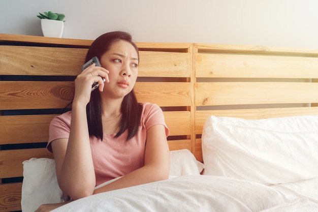 Femme contrariée a une conversation téléphonique sur son lit.