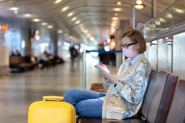 Femme contrariée par l'annulation d'un vol, écrit un message, assis dans un terminal d'aéroport presque vide