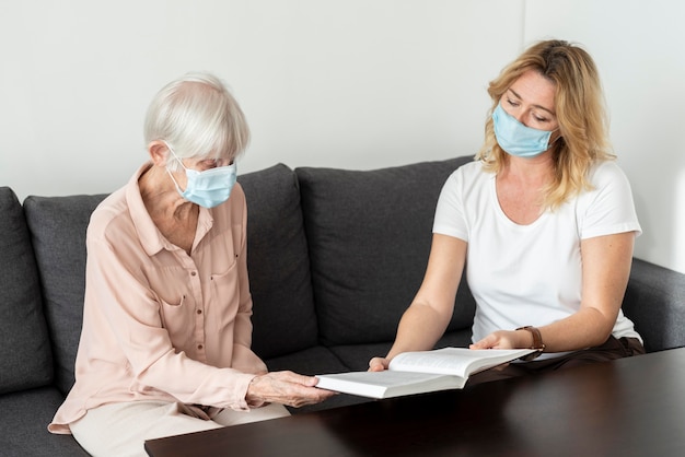 Photo femme conversant sur livre avec femme plus âgée à la maison de soins infirmiers