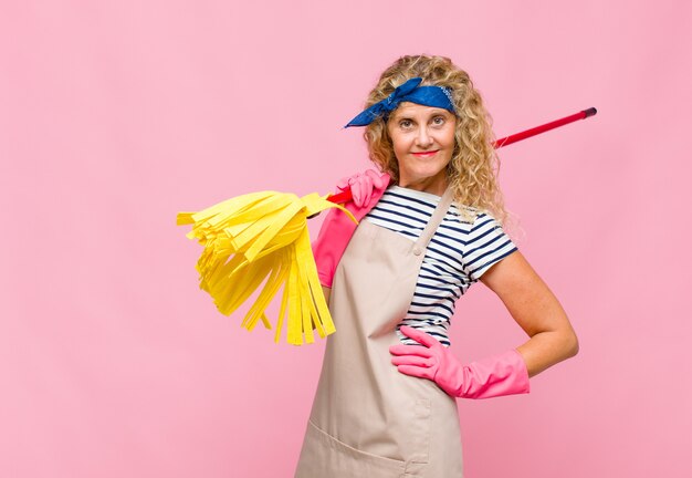 Photo femme cool d'âge moyen avec une vadrouille contre le mur rose