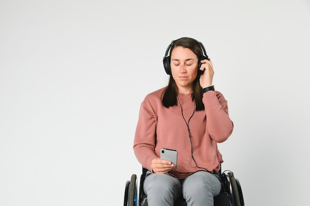 Femme cool dans un fauteuil roulant écoutant de la musique