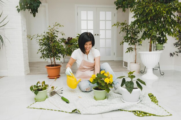 Photo une femme coréenne dans un tablier s'occupe des plantes et des fleurs dans un pot jardinage et floriculture