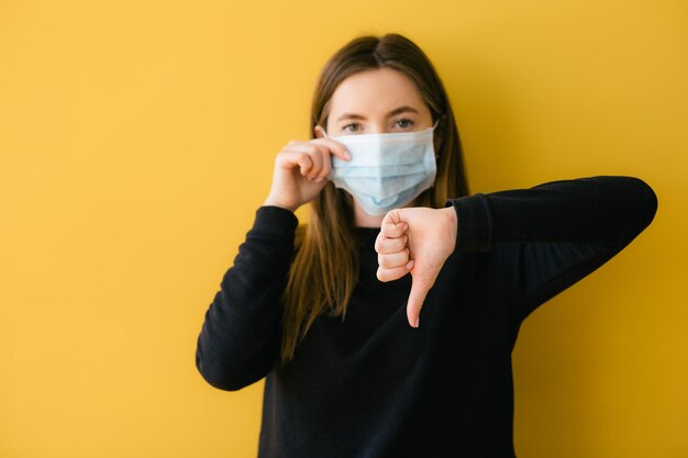 Femme coronavirus sur fond jaune dans la protection du visage du masque chirurgical