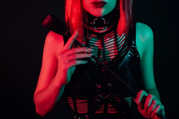 Femme avec un corps sexy dans de beaux sous-vêtements tient un fouet en cuir dans sa main pour le sexe BDSM