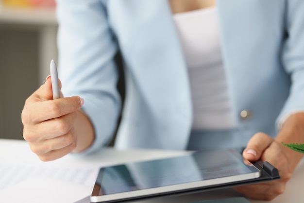 Femme en costume d'affaires tenant une tablette numérique et un stylet dans ses mains en gros plan