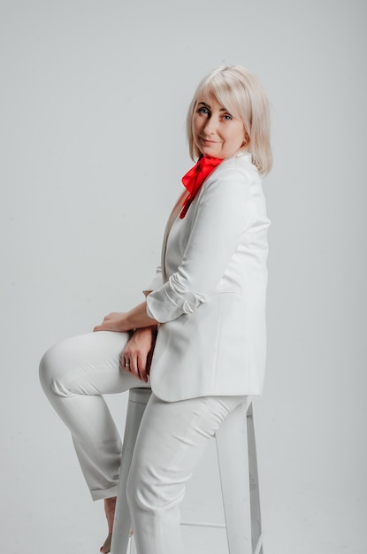 une femme en costume blanc avec une écharpe rouge sur fond blanc