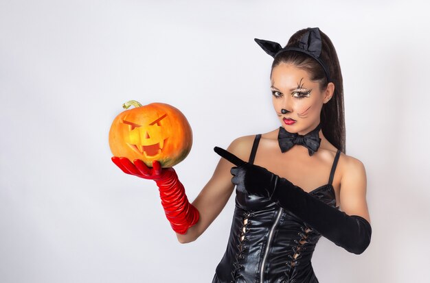 une femme en costume de chat tenant une citrouille