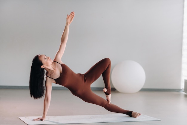 Une femme en costume marron fait du yoga dans une salle de fitness