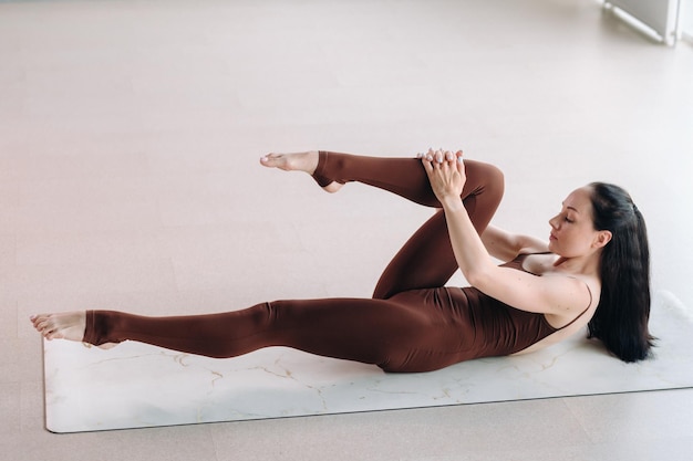 Une femme en costume marron fait du yoga dans une salle de fitness