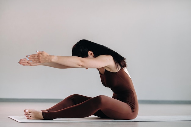 Une femme en costume marron fait du yoga dans une salle de fitness