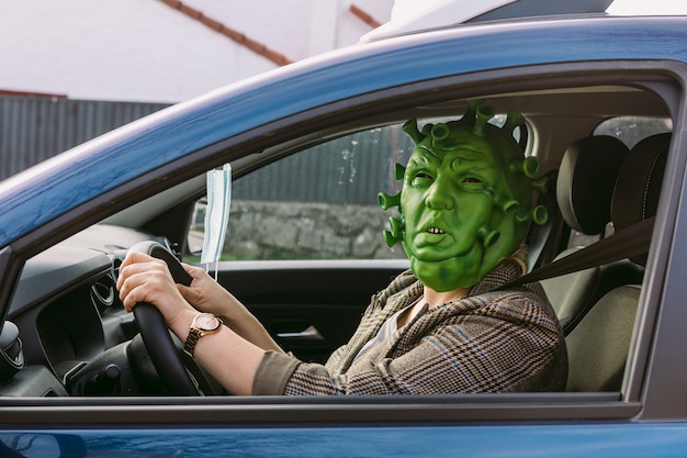 Femme en costume - masque de coronavirus Covid-19 au volant d'une voiture, furtivement par la fenêtre