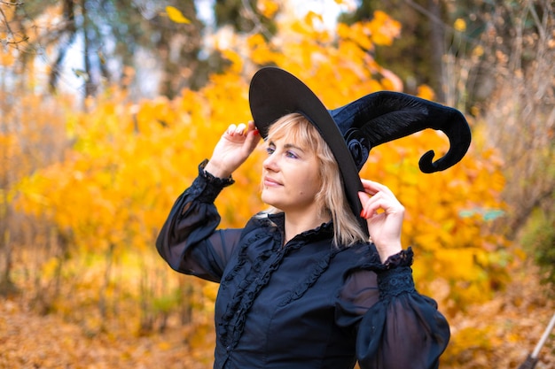 Une femme en costume de sorcière dans une forêt dense lors d'un rituel