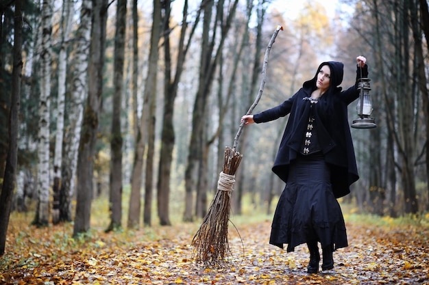 Une femme en costume de sorcière dans une forêt dense lors d'un rituel