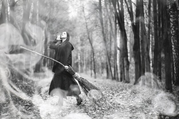 Une femme en costume de sorcière dans une forêt dense lors d'un rituel